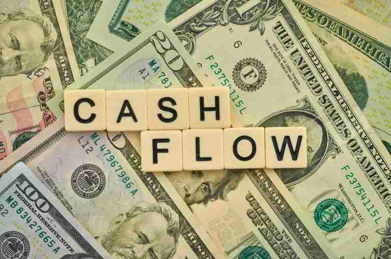 The Word Cash Flow spelled with scrabble letters laid over a pile of money